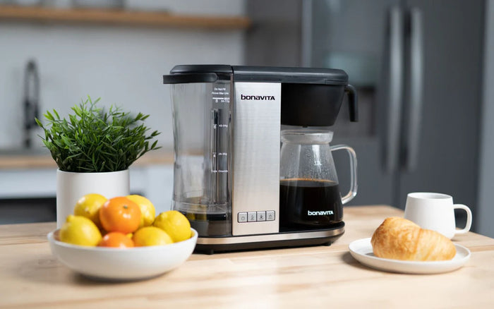 Bonavita Enthusiast Coffee Brewer, bowl of fruit, a croissant and a coffee cup on a kitchen table